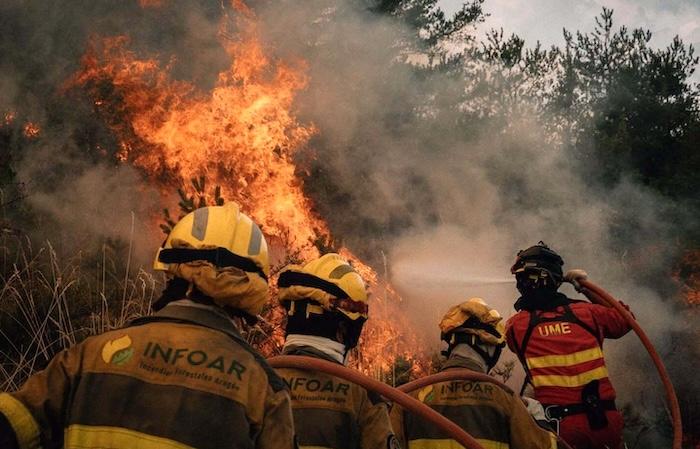 des pompiers de dos en tenue en train de lutter contre les flammes cet été lors des incendies en espagne