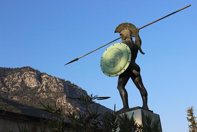 Vue d'une statue représentant un guerrier spartiate, une montagne s'étalant à l'arrière-plan de l'image