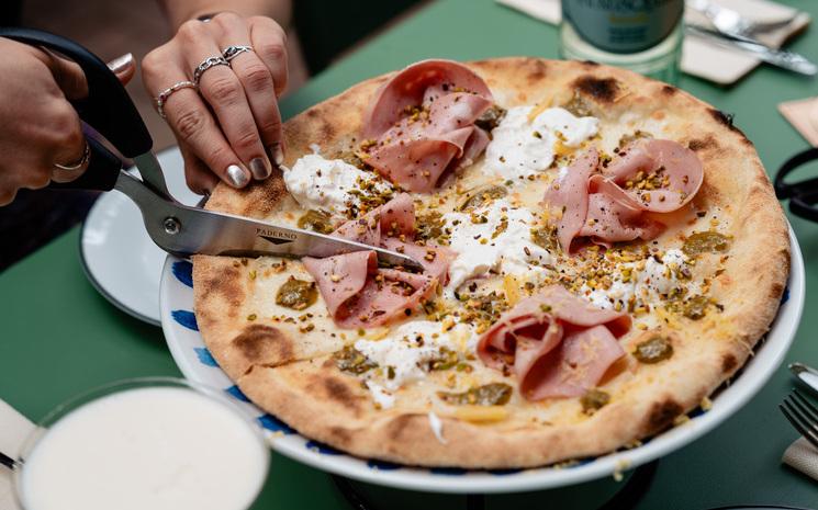 Femme en train de couper une pizza romaine chez Monti à Berlin