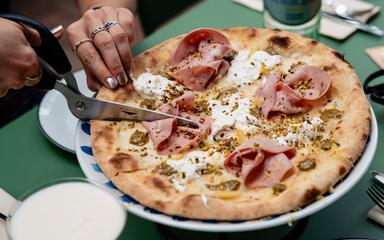 Femme en train de couper une pizza romaine chez Monti à Berlin
