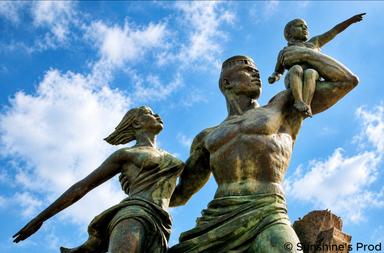 Monument de la Renaissance africaine à Dakar, représentant trois figures en bronze tournées vers l’horizon sous un ciel bleu.