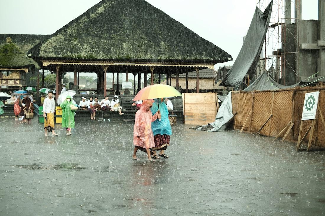 des gens en poncho sous un parapluie sous la pluie