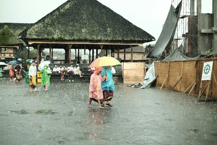 des gens en poncho sous un parapluie sous la pluie
