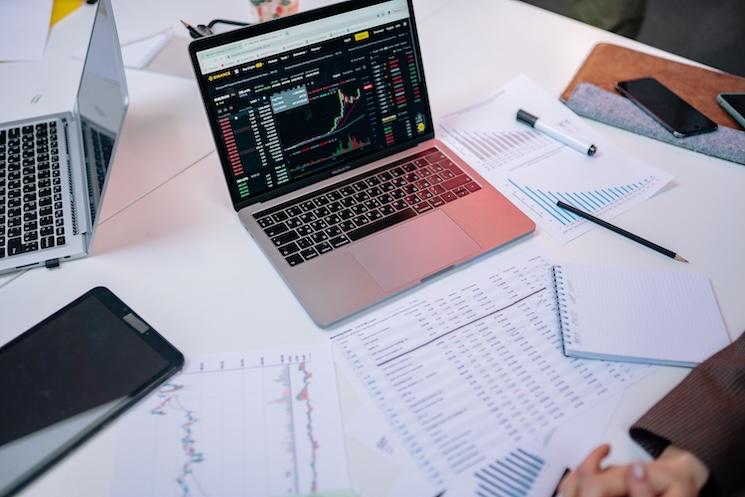 ordinateur ouvert sur des feuilles de statistiques sur un bureau