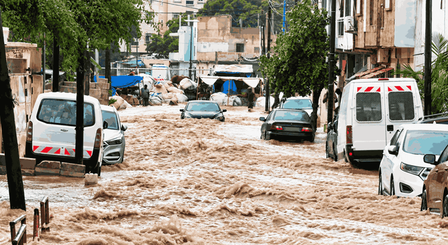 Rue de Dakar submergée par de violentes inondations, avec plusieurs voitures partiellement immergées dans un puissant courant d’eau boueuse après de fortes pluies au Sénégal.