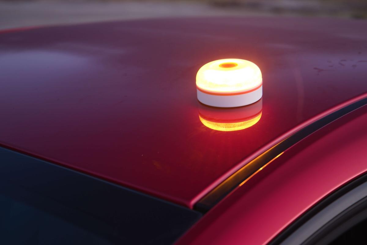 Balise lumineuse V16 orange allumée sur le toit d'une voiture, dispositif de signalisation des pannes en Espagne.