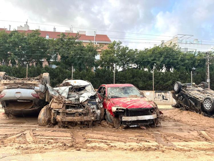 Quatre voitures détruites, dont deux retournées, couvertes de boue et de débris après les inondations de la DANA à Valence en octobre 2024.