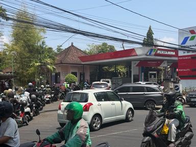 Station service avec longue file d'attente de voitures et scooter