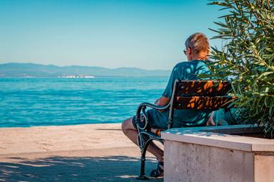 Un retraité sur banc face à la mer en Espagne