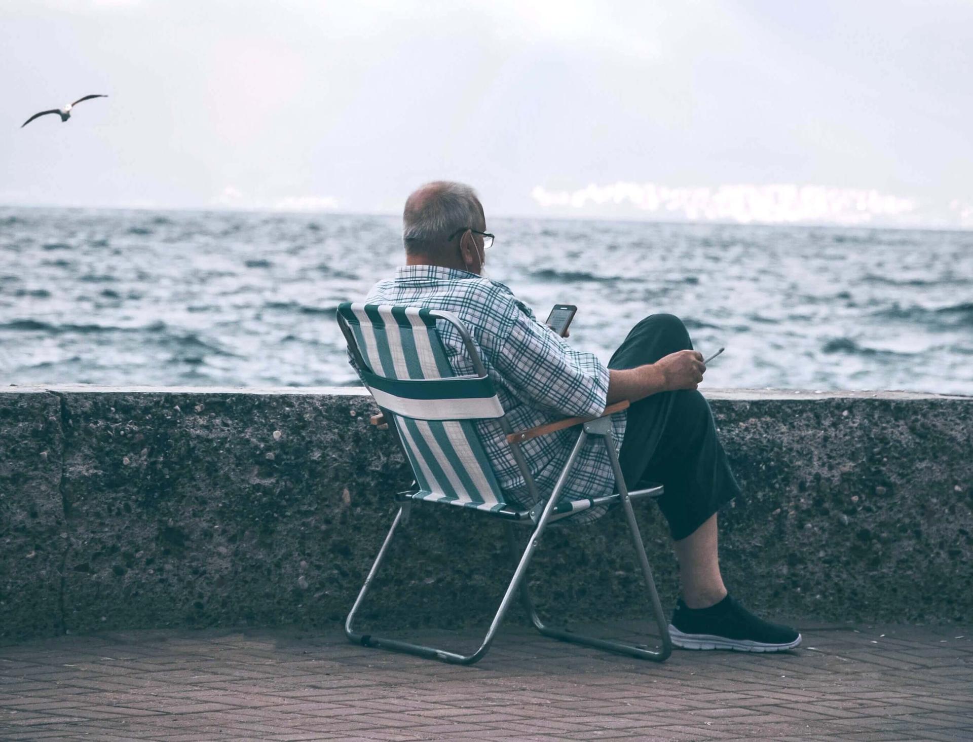 un retraite espagnol seul de dos assis sur une chaise face à la mer