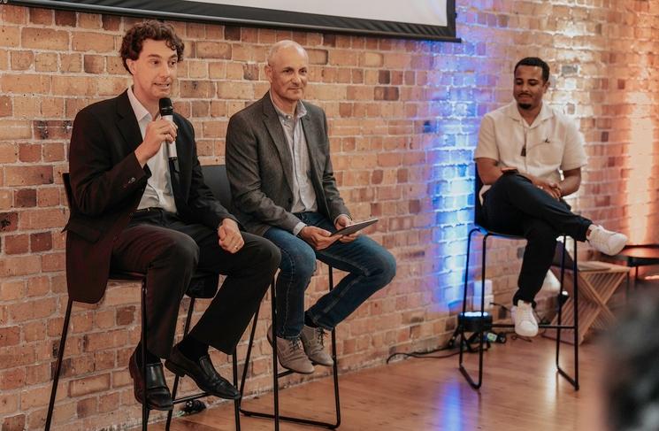 2 speakers assis sur une chaise haute et un animateur