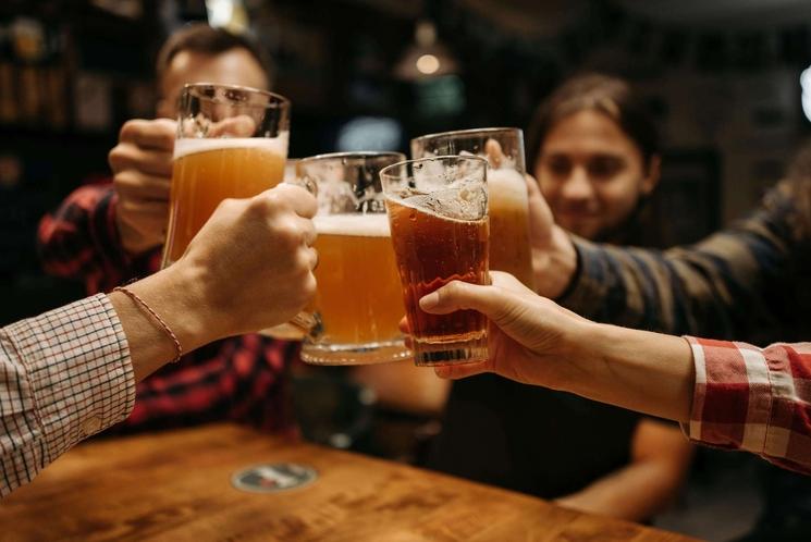Amis de différentes nationalités trinquent en souriant et boivent leur bière.
