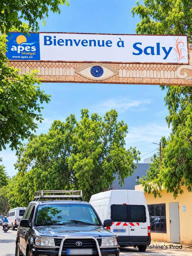 Panneau « Bienvenue à Saly » à l’entrée de la station balnéaire sénégalaise, près de la plage et de l’océan Atlantique.