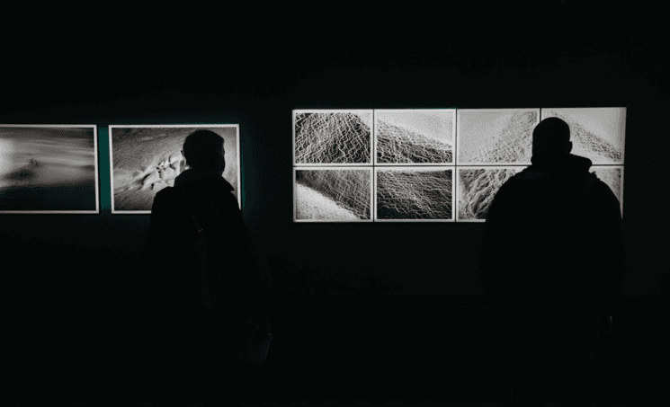 Des personnes de dos regardant des photos pendant une exposition