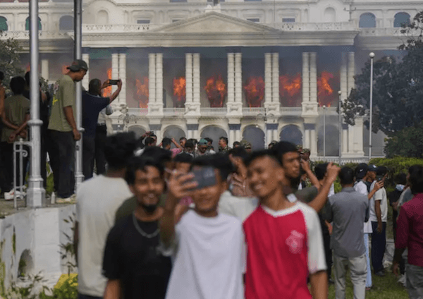 Des jeunes Népalais se prennent en photo devant le siège du gouvernement népalais incendié par des manifestants à Katmandou, le 9 septembre 2025. AP - Niranjan Shrestha