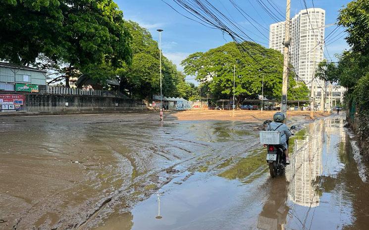 Une moto avance dans une rue couverte de boue a Chiang Mai apres de fortes inondations