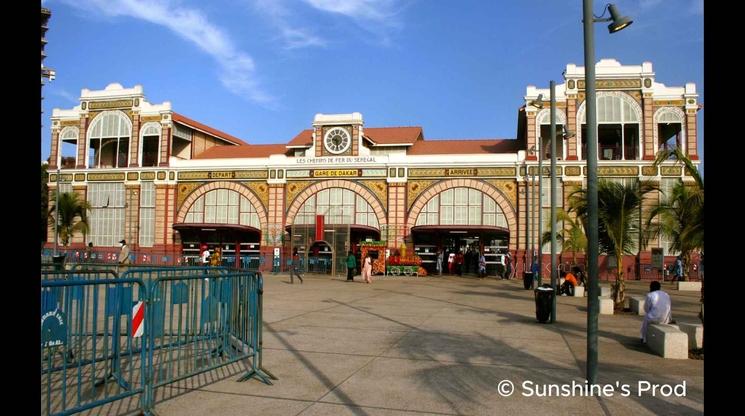 Façade de la Gare de Dakar au Sénégal, avec ses grandes arches, ses décorations historiques et son esplanade animée à l'entrée.