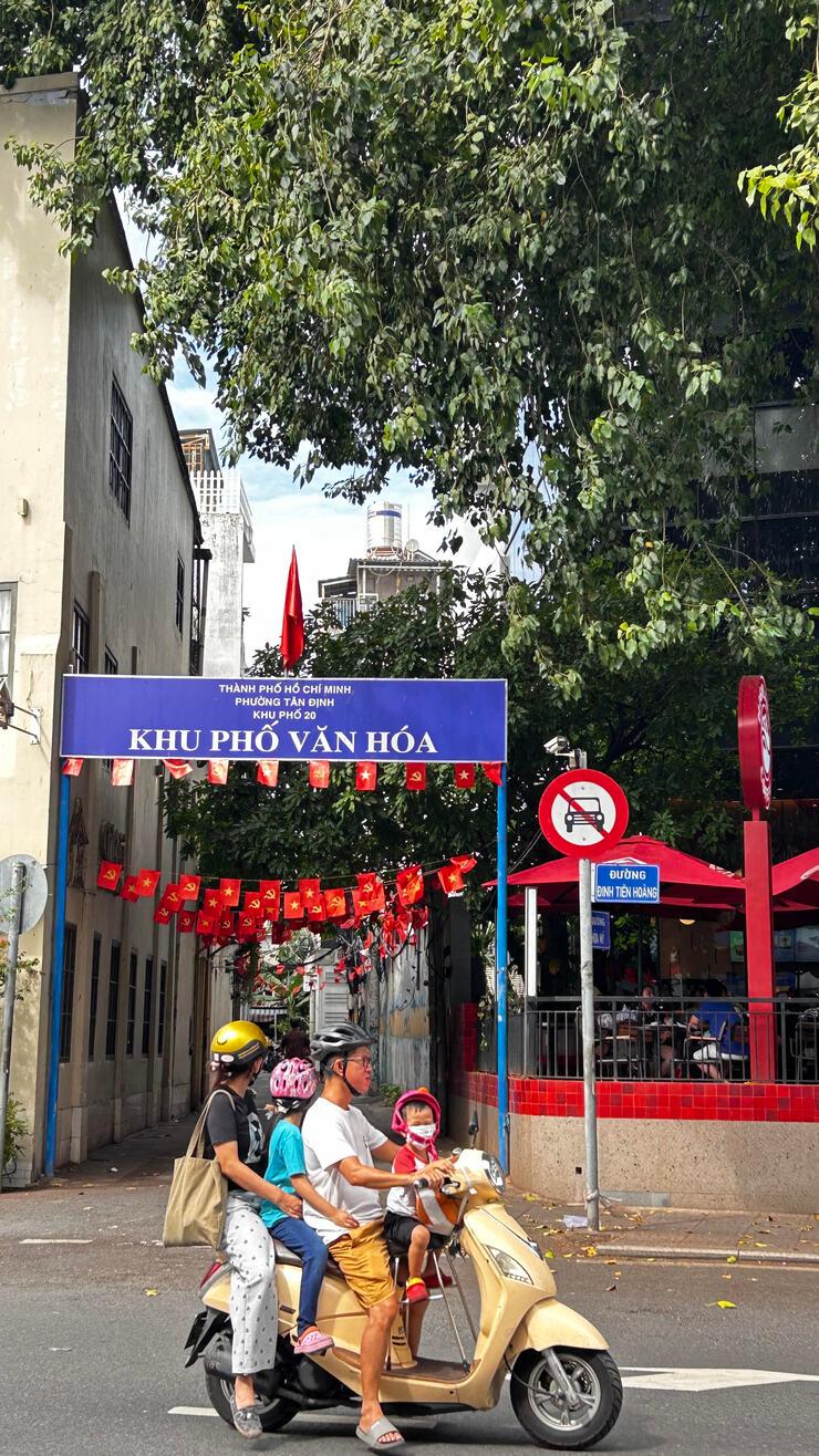 À Đa Kao, qui fait partie de la ville, une famille sur un scooter passe devant une ruelle.