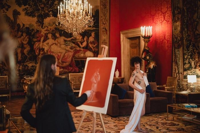 un artiste dessine un modèle de nue enveloppée d'un drap blanc