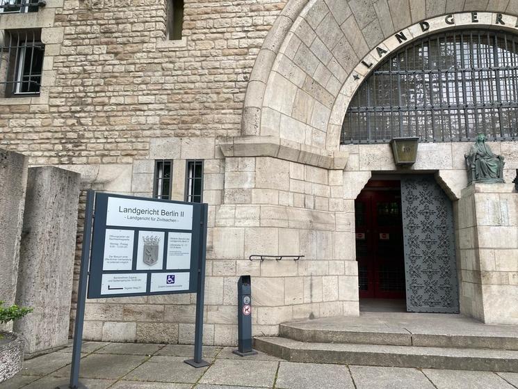 Entrée du tribunal de district de Charlottenbourg avec un panneau indicatif devant un bâtiment en pierre blanche et une porte en bronze ouverte