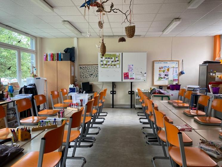 La salle de classe de la Gartenarbeitsschule à Friedrichshain-Kreuzberg. Rangées de tables et chaises posées dessus.