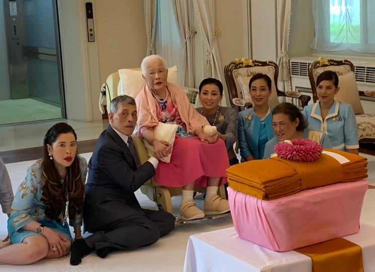 La reine-mère de Thaïlande entourée de sa famille, tient la main de son fils le roi Rama X