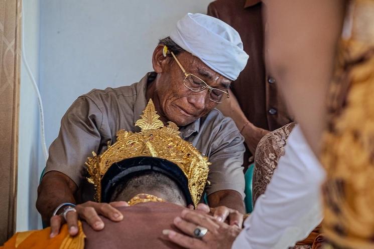 un homme âgé qui ferme les yeux pour bénir un homme lors de son mariage à bali