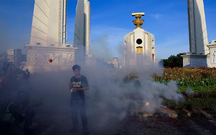 Un manifestant anti-gouvernement devant le Monument de la democratie a Bangkok au mileu de fumigenes