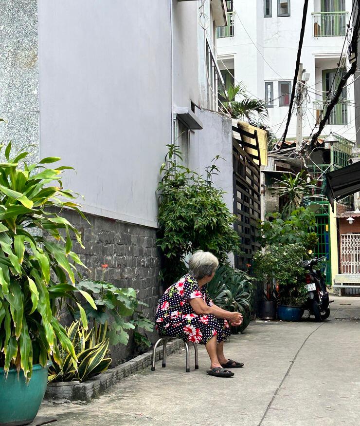 Une personne âgée est assise dans une ruelle, aussi dans l’ancien 4ᵉ arrondissement de la ville, profitant de la fraîcheur.
