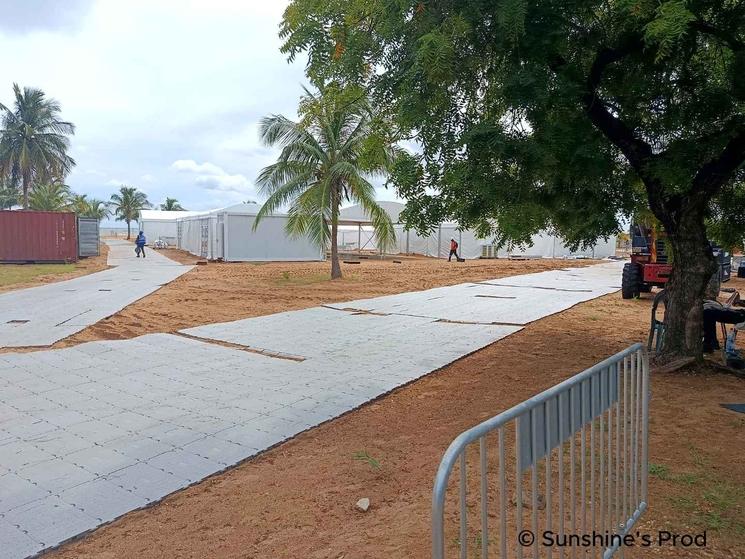 Installation de structures temporaires en bord de plage à Saly, entourées de palmiers et de voies d’accès aménagées.