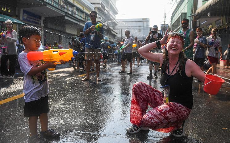Un enfant thailandais tire au pistolet a eau sur une touriste durant les festivites de Songkran