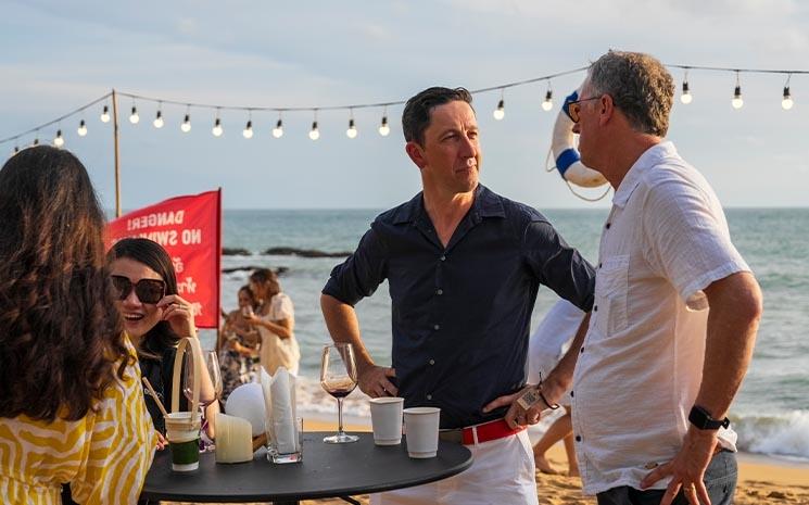 Des participants au salon du tourisme en Thailande TTM+ 2024 discutent sur la plage lors du cocktail de lancement