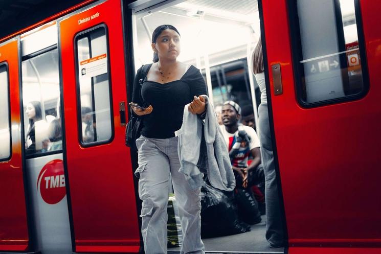 Jeune femme catalane sortant du métro Barcelonais. Elle se dirige vers la sortie, le portable à la main et la tête tournée vers la droite.