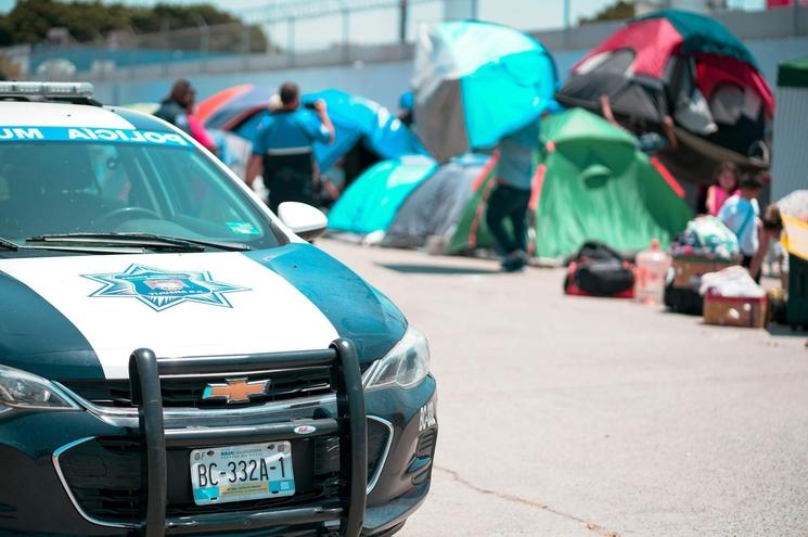 Une voiture de police devant des migrants