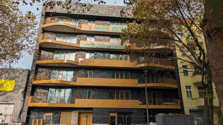 Vue de face de l'immeuble, avec papier de protection sur les balcons et bâches plastifiées bleues aux fenêtres