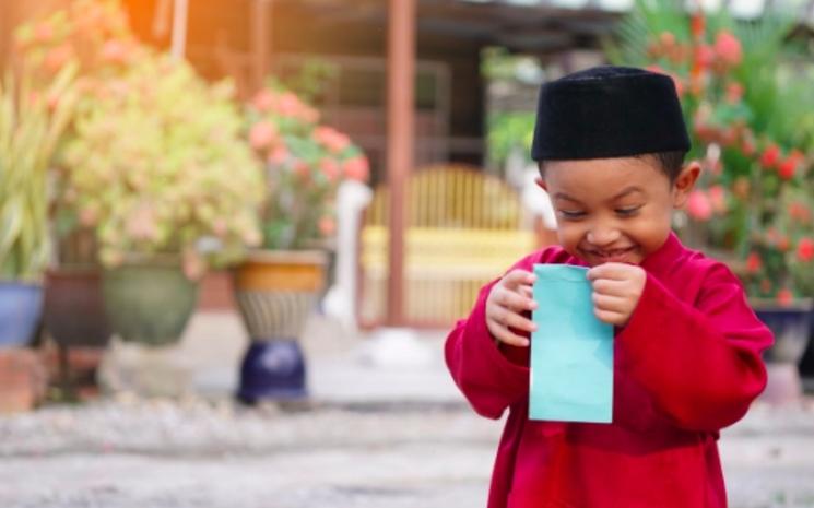 Un enfant malais ouvrant son enveloppe verte (copyright muslim.sg)