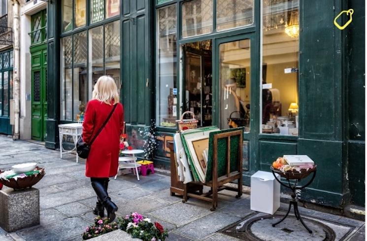 Femme se baladant dans la rue devant un vendeur de toile de peintures