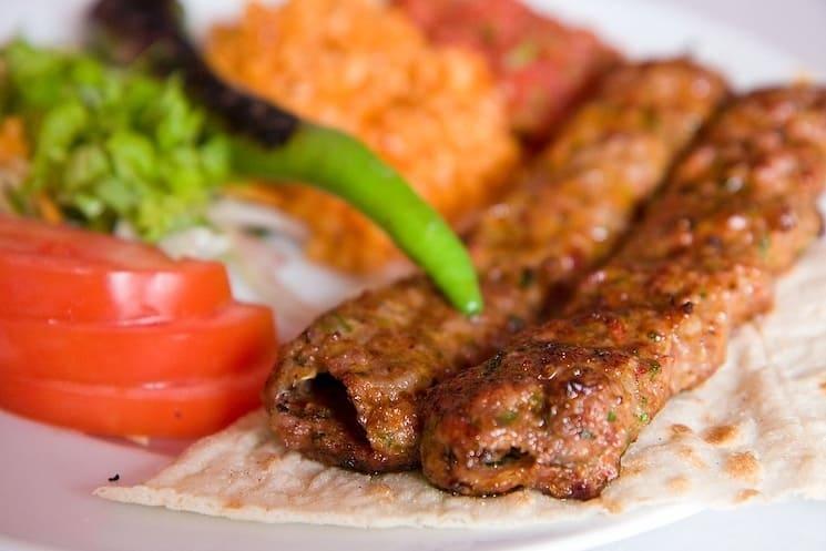 Adana kebap, spécialité turque épicée composée de viande d’agneau hachée, grillée sur des brochettes et servie avec du pain lavash, du boulgour et des légumes grillés.