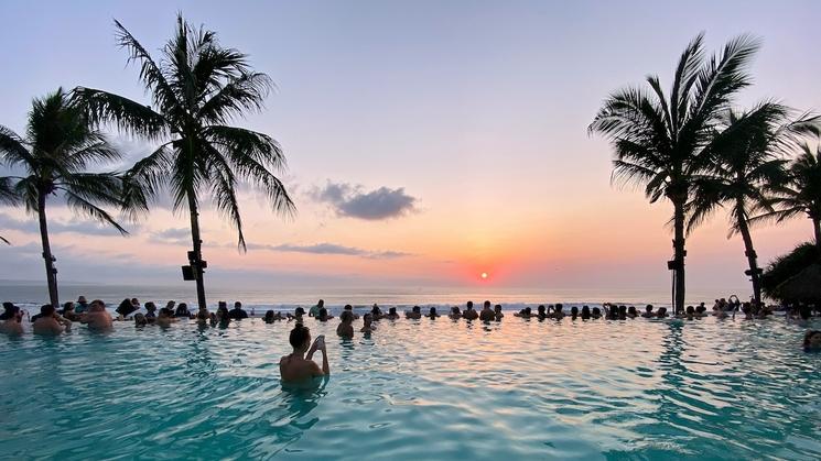 beach club avec palmiers et vue sur le coucher de soleil à seminyak, bali