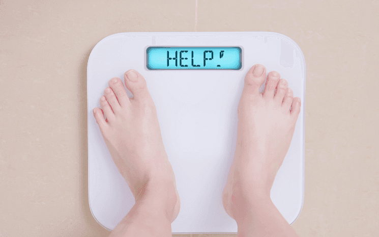 Une personne se pesant sur une balance affichant HELP, signifiant qu'il faut prendre la résolution de se remettre en forme en 2023
