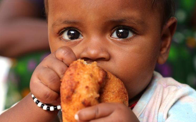 Un enfant indien mangeant une cuisse de poulet