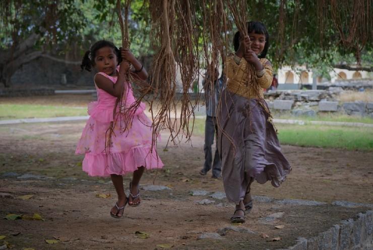 Fillettes se balançant à des racines de banyan