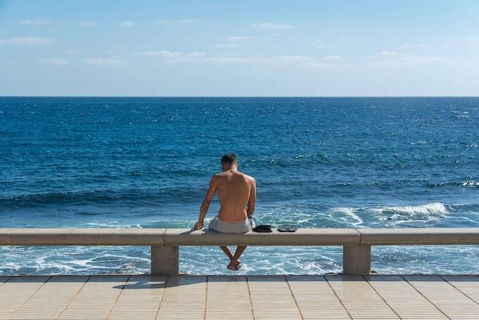 homme torse nu de dos face à la mer