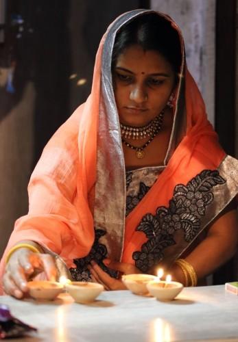 femme allumant des diyas de diwali