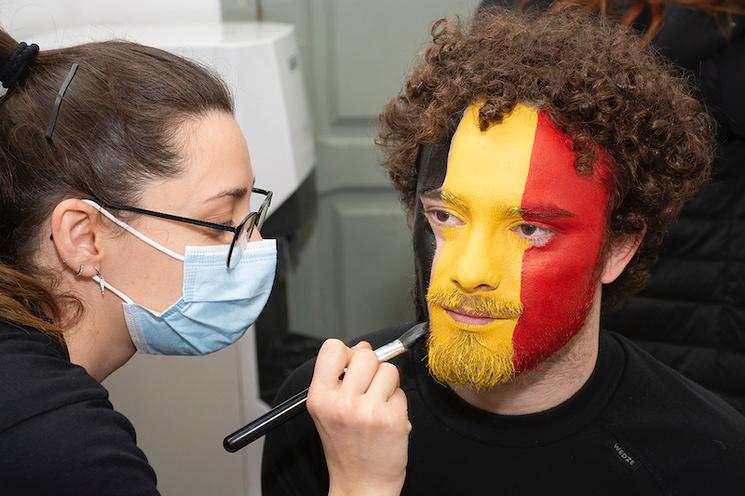 un jeune homme maquille aux couleurs de la belgique