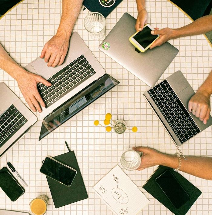 mains de freelance en train de travailler sur leurs ordinateurs sur une table