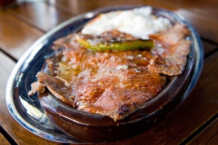 İskender kebap, spécialité emblématique de Bursa, composé de fines tranches de viande d’agneau servies sur du pain pita, nappées de sauce tomate et de beurre fondu, accompagnées de yaourt.