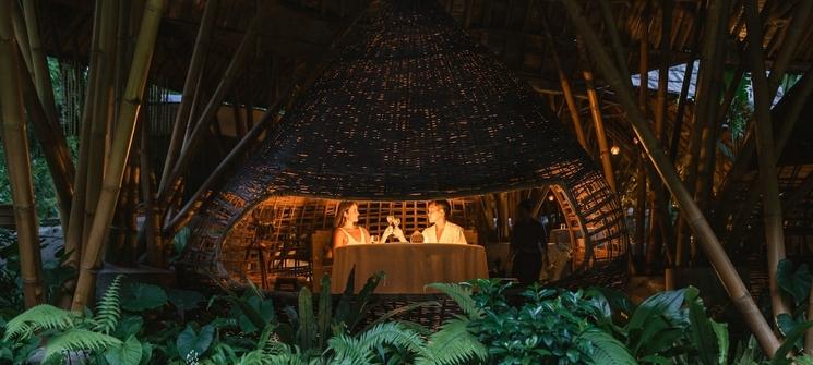 un homme et une femme à table dans une hutte en bambou au restaurant kubu à ubud