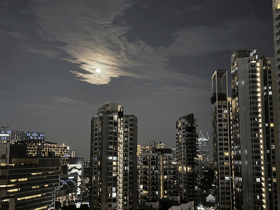 La lune dans le ciel entre les bâtiments à Singapour, de nuit.