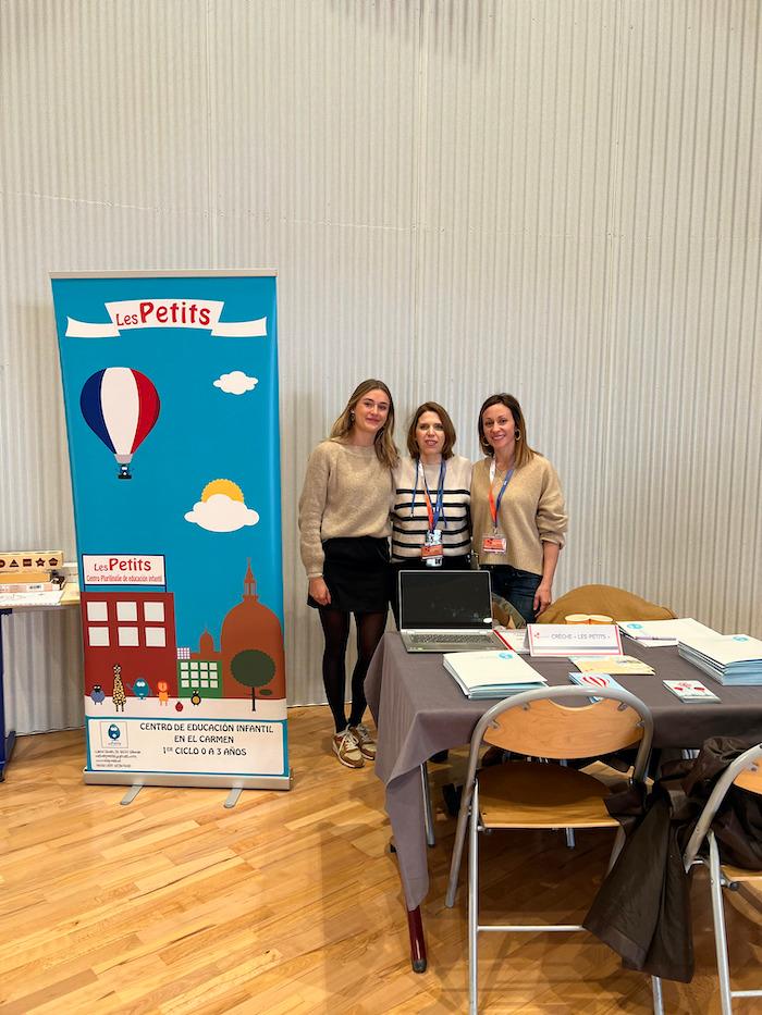 Trois femmes posant devant le stand Les Petits lors des Portes Ouvertes du lycée français de Valence